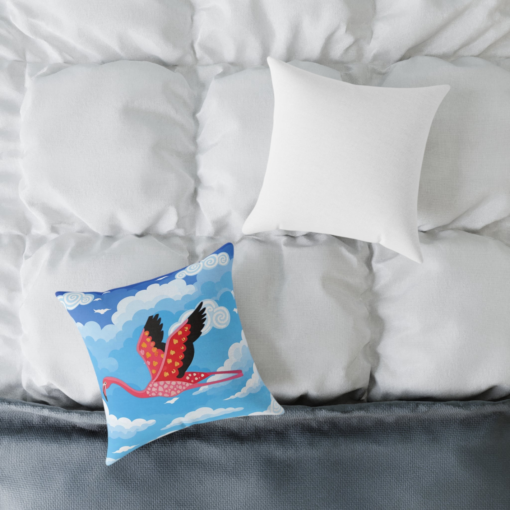 Decorative pillow with a flamingo design on a bed with white pillows and gray bedding.