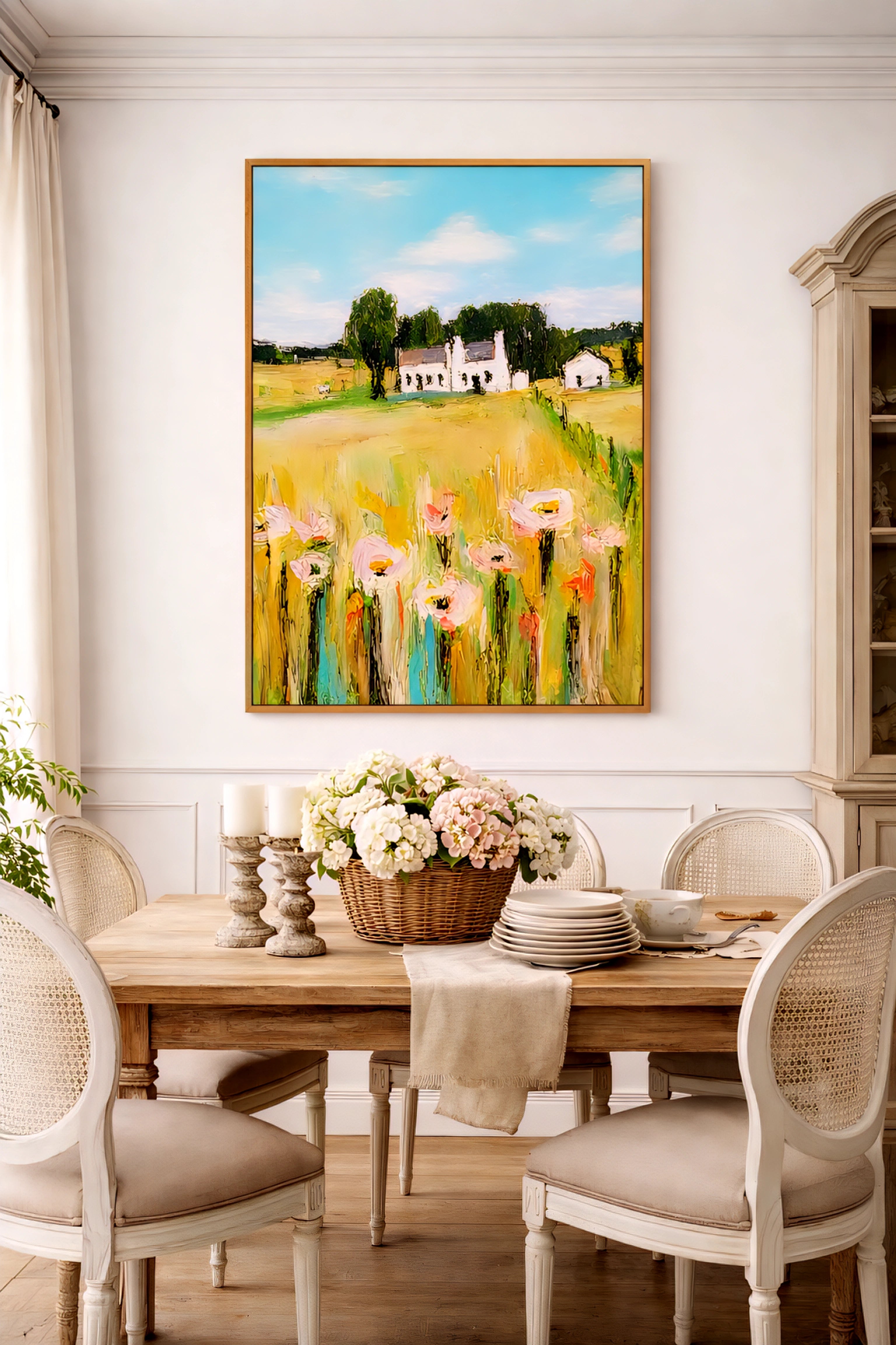 French country dining room with large farmhouse landscape digital wall art in light wood frame above table with flowers and neutral decor