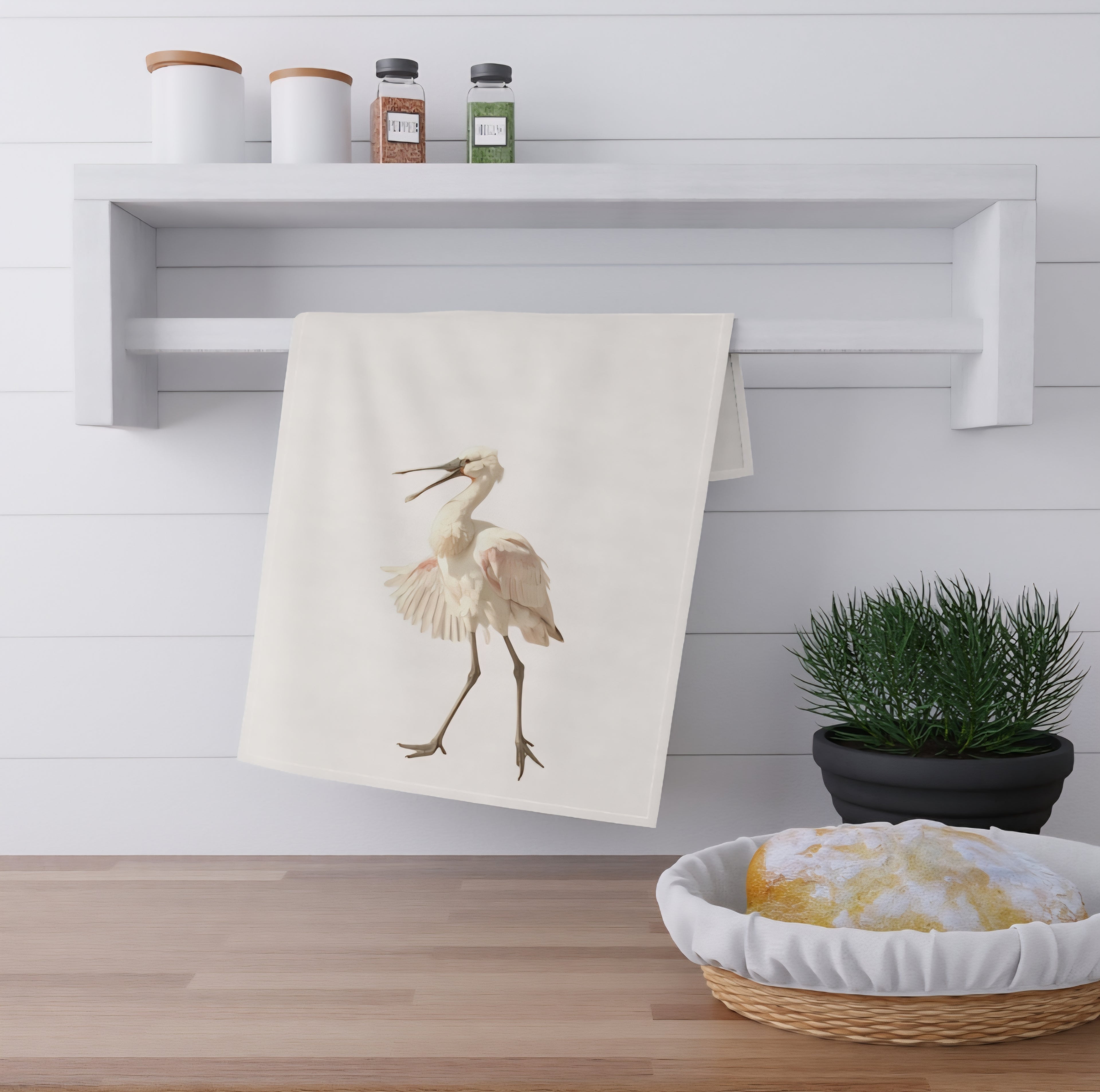 Towel made from digital art file with a bird design hanging on a wall next to a shelf with containers and a plant.