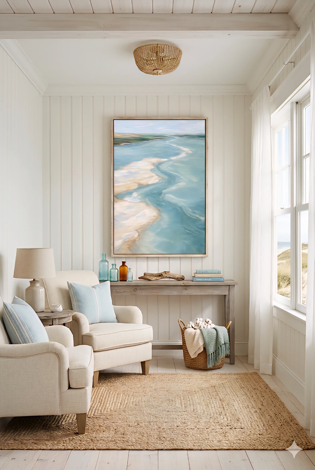 Coastal living room with ocean artwork above console table, neutral seating, woven rug and beach house decor
