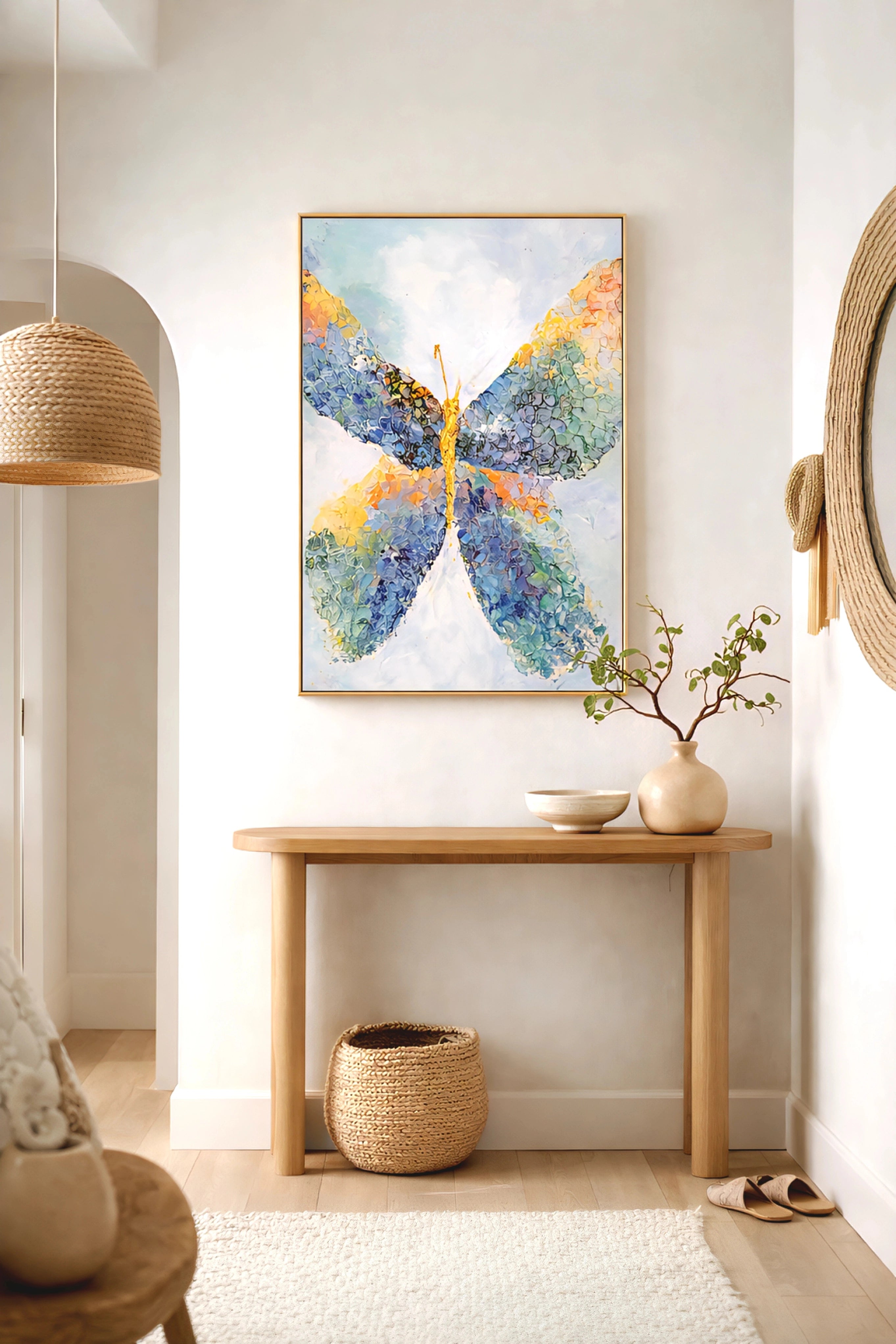 Colorful abstract butterfly wall art in gold frame above wood console table with neutral decor, woven textures, and soft organic entryway styling