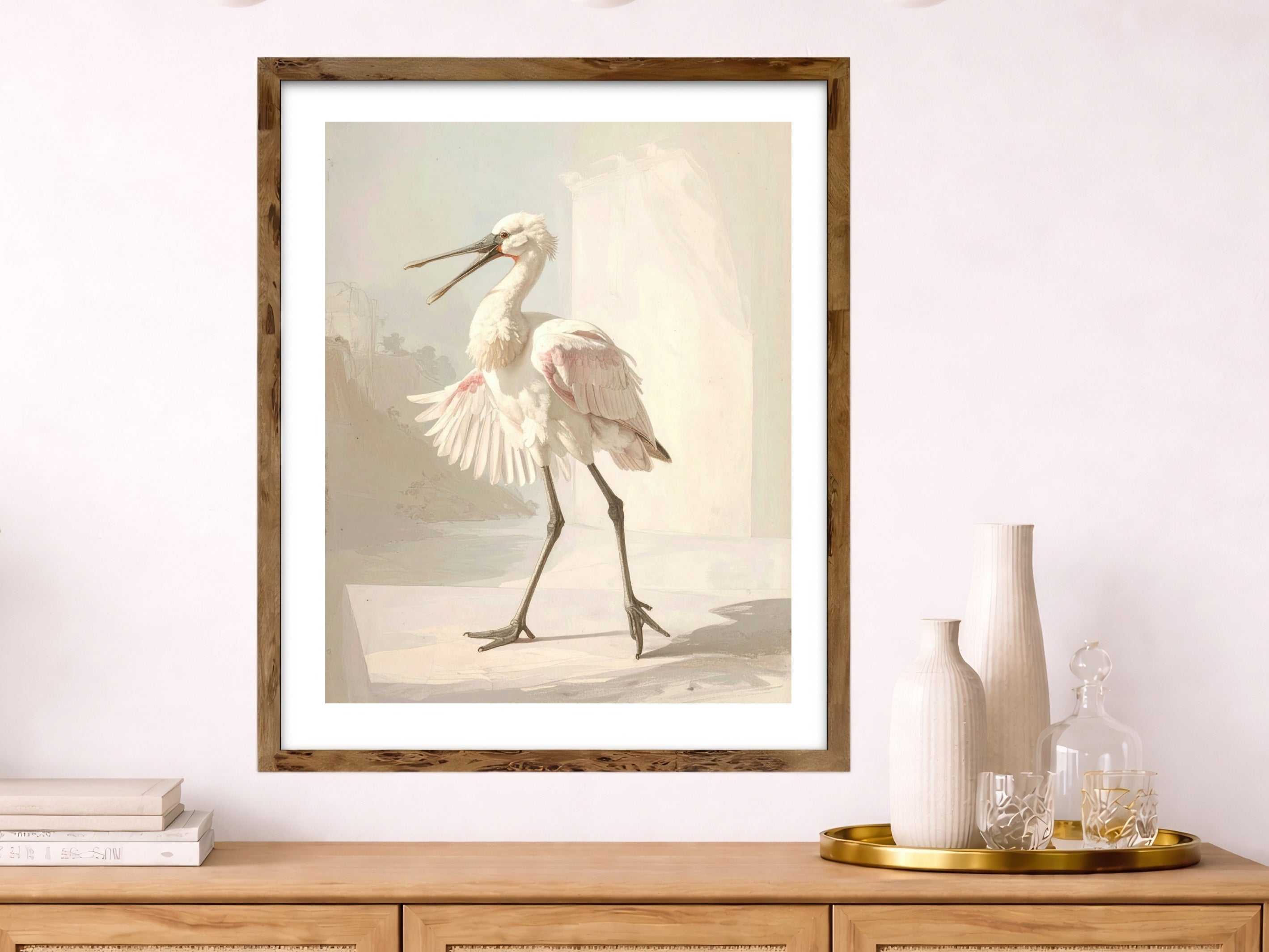 Framed artwork of a soft  warm neutral spoonbill bird on a wall above a wooden cabinet.