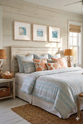 Coastal bedroom with three framed digital  ocean prints above bed with blue striped bedding and coral pillows