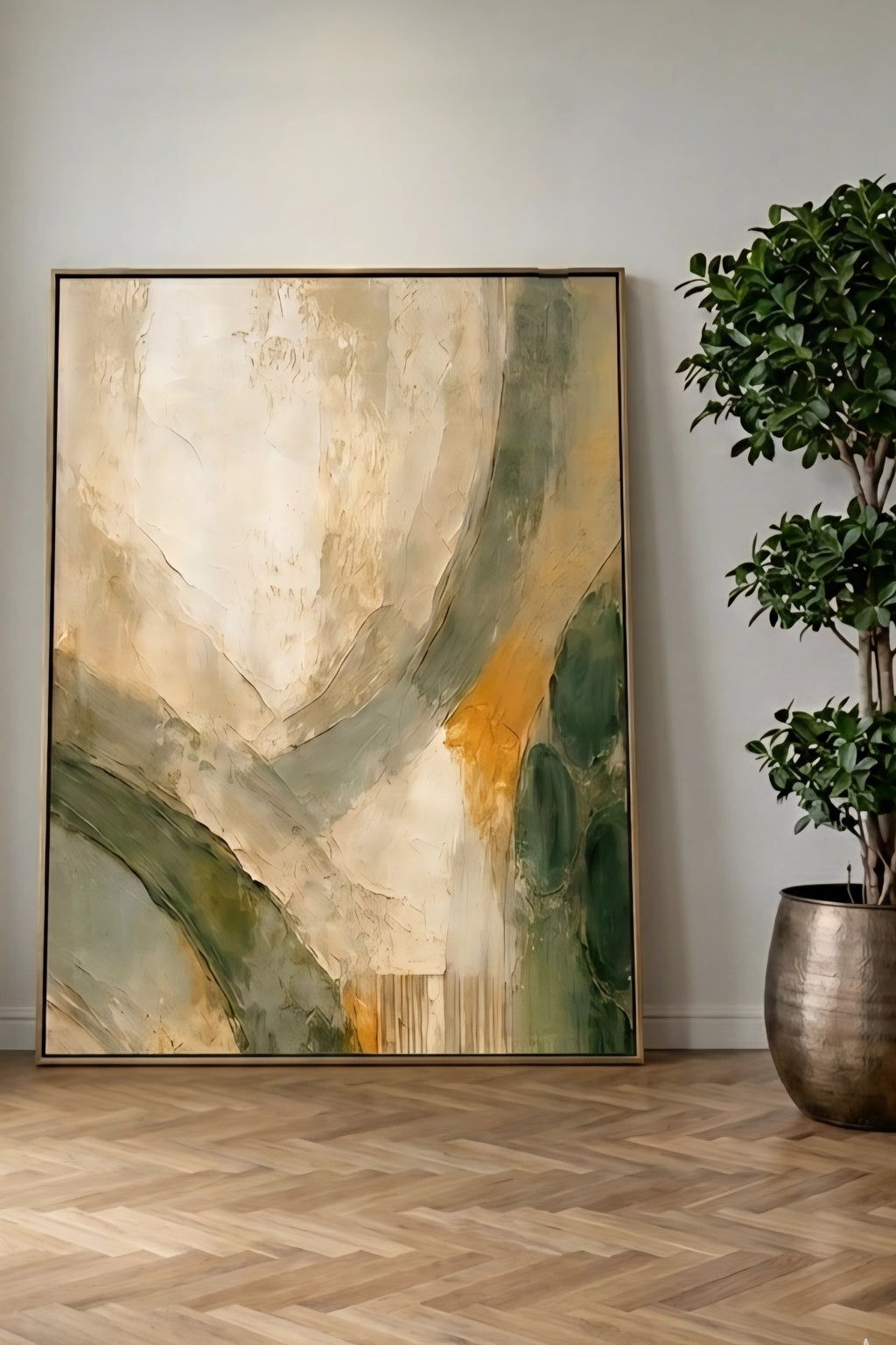 Earth tone abstract wall art in modern frame leaning against wall with wood floors and potted plant, neutral green and gold decorinspo