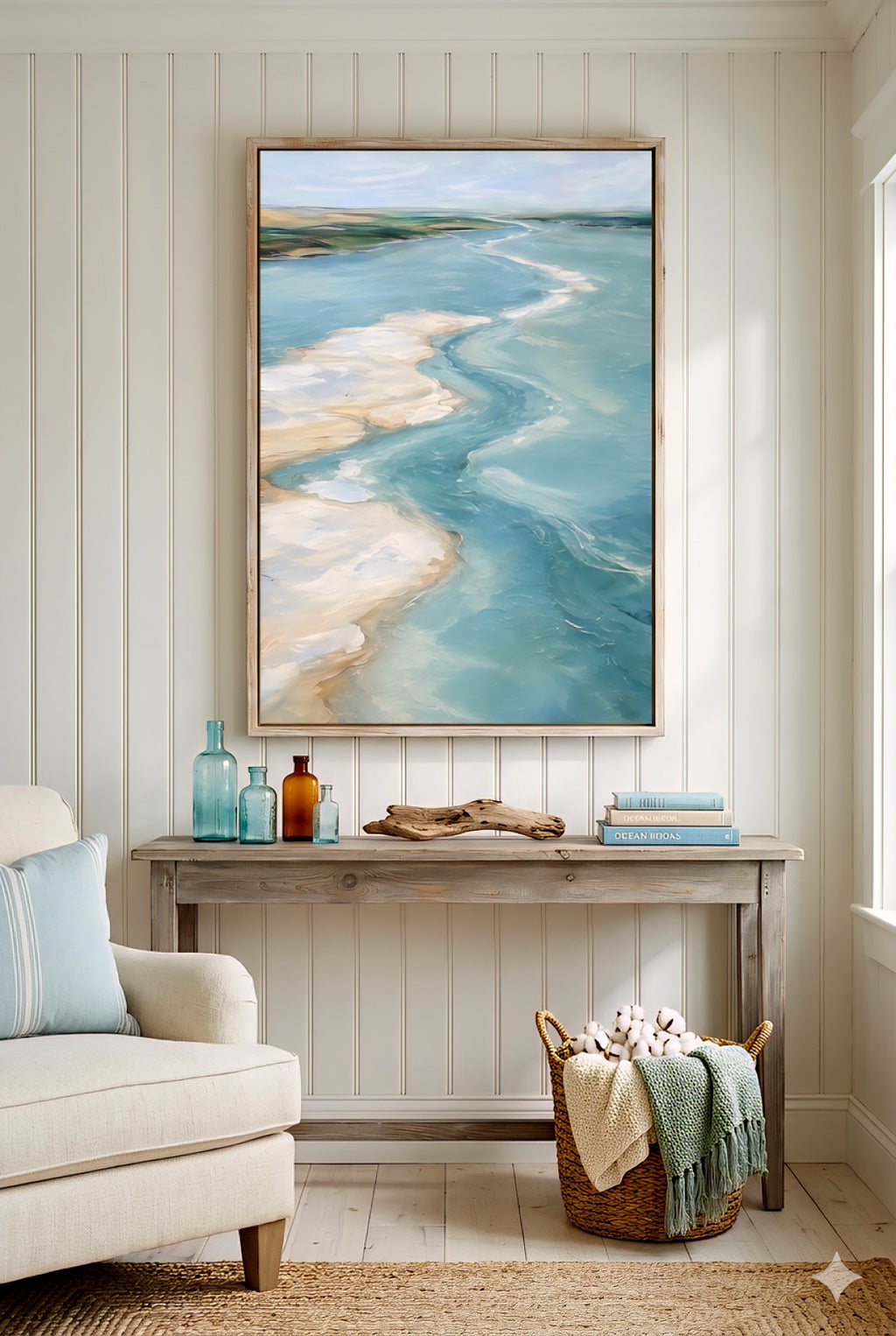 Coastal console table styling with large ocean artwork, glass bottles, driftwood decor and woven basket in beach style room