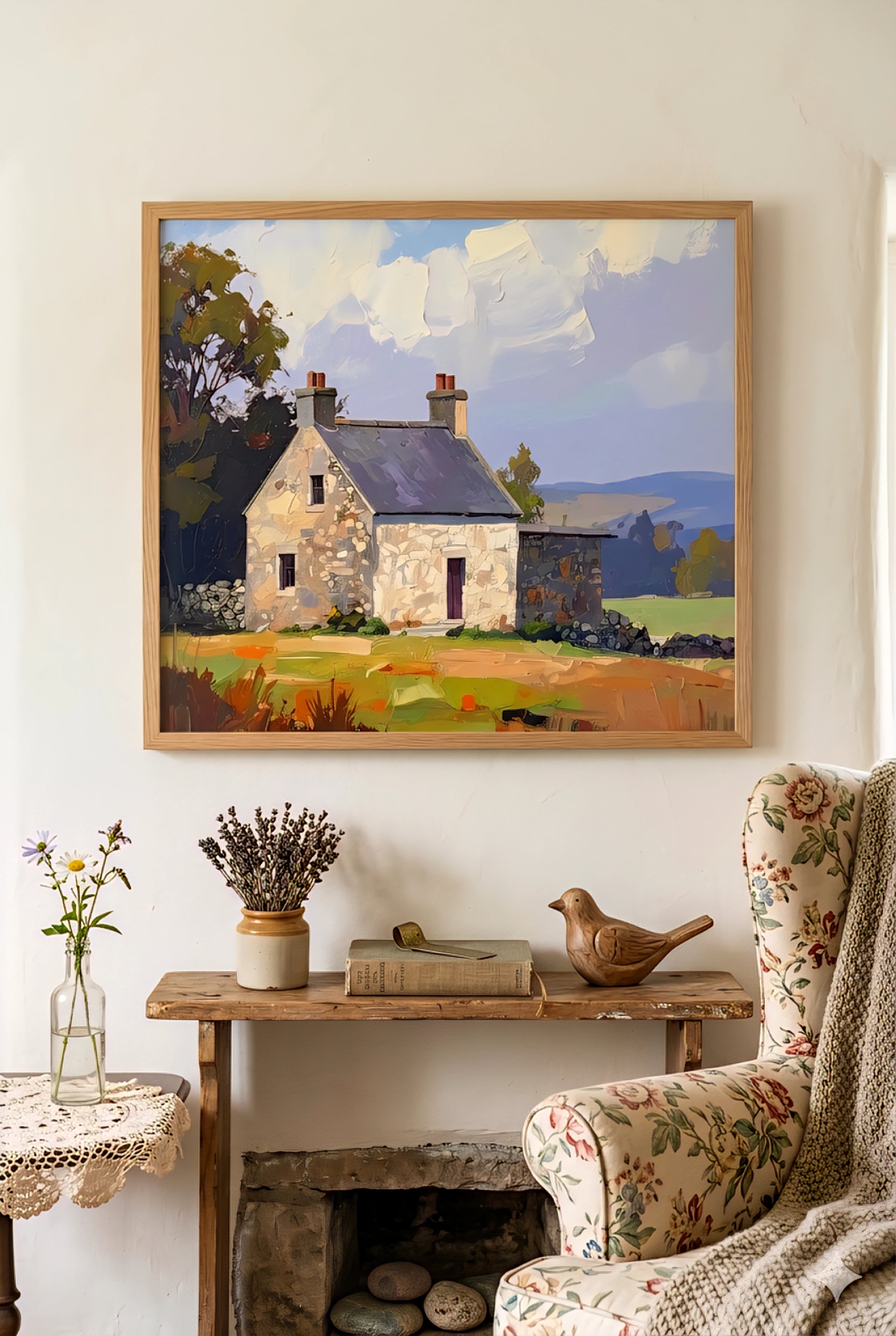 Rustic cottage wall art landscape in warm countryside colors, framed horizontal print styled above vintage wood bench with floral armchair and farmhouse decor in a cozy neutral living space